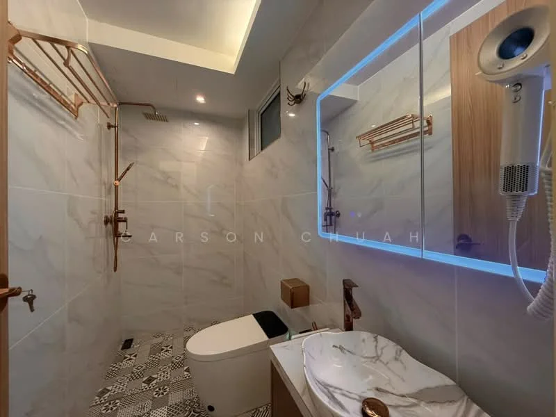 Bathroom features: marble tile flooring, white tiled walls, gold fixtures, walk-in shower with glass enclosure, rain shower head, handheld shower, one-piece toilet, single-sink vanity with marble top, framed mirror with LED backlighting, wood cabinetry, wall-mounted hairdryer, decorative wall hooks; style: modern.