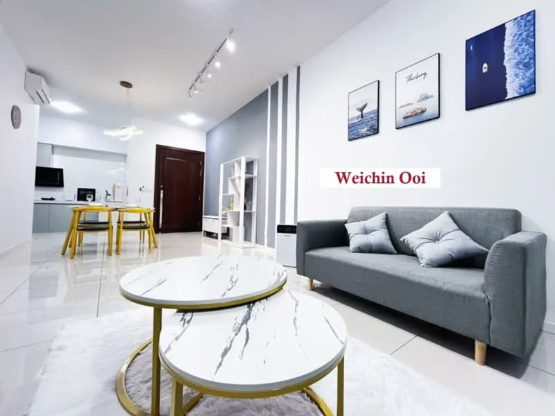 Living features: grey fabric sofa, decorative cushions, round coffee table with marble top, white area rug, wall-mounted TV, shelving unit, recessed ceiling lights, air conditioning unit, white painted walls, grey accent wall, dining area visible in background, dining table with yellow legs; style: modern.