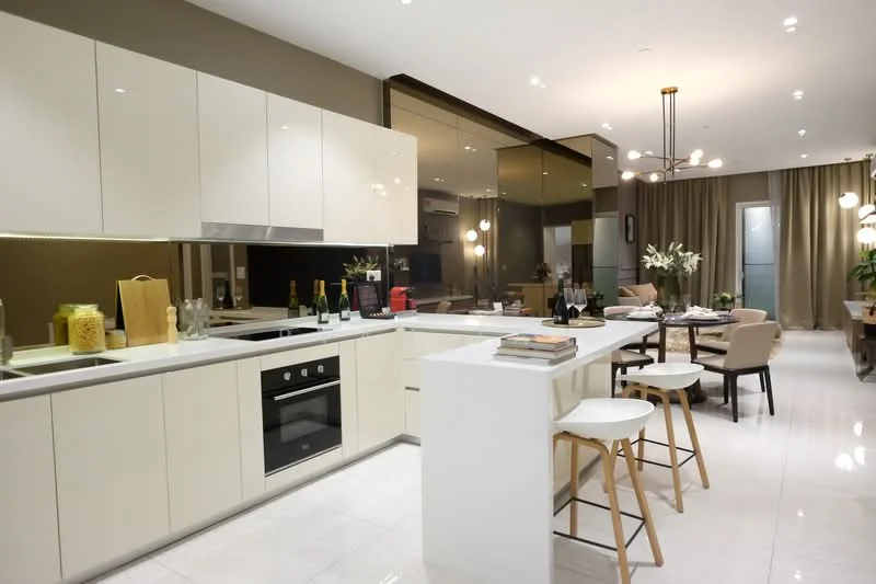 Kitchen features: white cabinetry with flat-panel design, stainless-steel built-in oven, stainless-steel cooktop, white quartz countertop, single-bowl stainless-steel sink, chrome pull-down faucet, bar stools with wooden legs, wine bottles on countertop, recessed downlights, pendant lighting above island, mirror backsplash, open shelving, marble tile flooring, cream painted walls; style: modern. Dining features: round dining table, upholstered dining chairs, decorative centerpiece, wall-mounted TV, curtains, indirect lighting, plant in corner; style: modern.