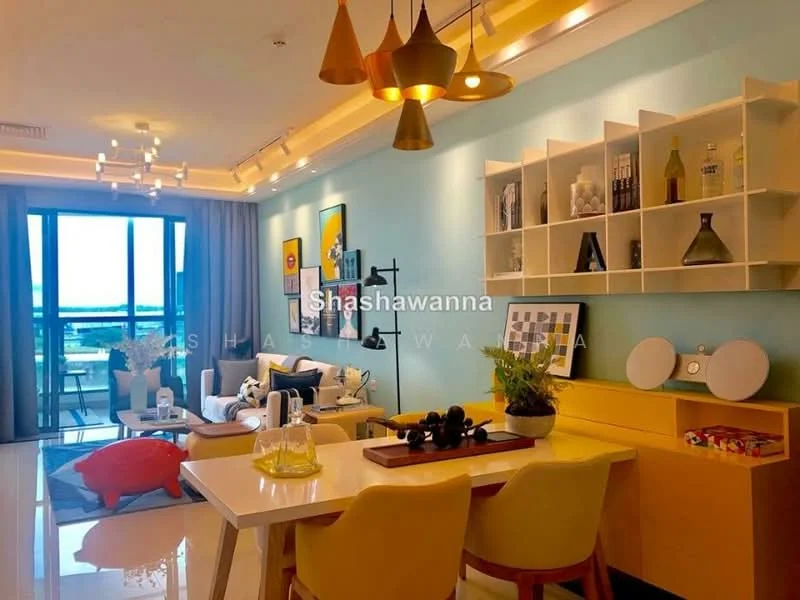 Living features: blue painted walls, white ceiling with recessed lighting, large floor-to-ceiling windows, sliding glass door leading to balcony, cream-colored sofa, yellow dining chairs, white dining table, decorative wall shelves, abstract artwork, pendant lights in various colors, coffee table, area rug with geometric pattern, potted plants, decorative vases, TV console; style: modern; view: city.