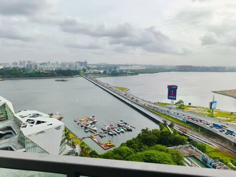 Exterior type: high-rise condominium; features: waterfront view, city skyline in background, roadway along water, boats in marina, green landscaping, urban development visible; style: modern.