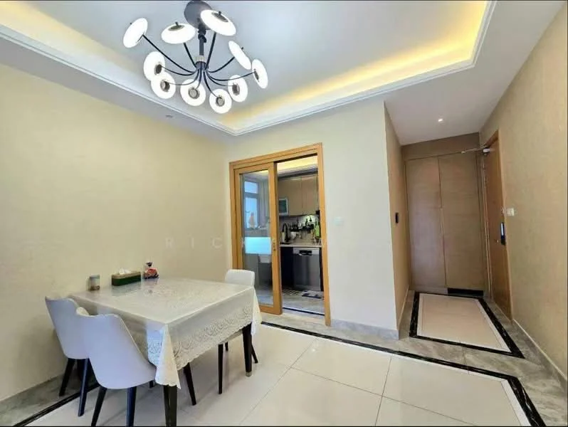 Dining features: dining table with lace tablecloth, 4 upholstered dining chairs, chandelier with circular design, cream painted walls, recessed ceiling lights, marble tile flooring, sliding glass door, decorative wall paneling, open doorway leading to kitchen, window with view, corner plant decoration; style: modern. Hallway features: cream painted walls, marble tile flooring, wooden door, recessed lighting, decorative wall paneling; style: modern.