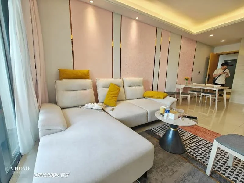 Living features: L-shape sectional sofa in light grey, yellow accent cushions, coffee table with round top and dark base, area rug with geometric pattern, floor-to-ceiling windows, curtains in light fabric, recessed ceiling lights, wall-mounted TV, decorative wall panels in pink and cream, marble flooring; style: modern; view: city.
