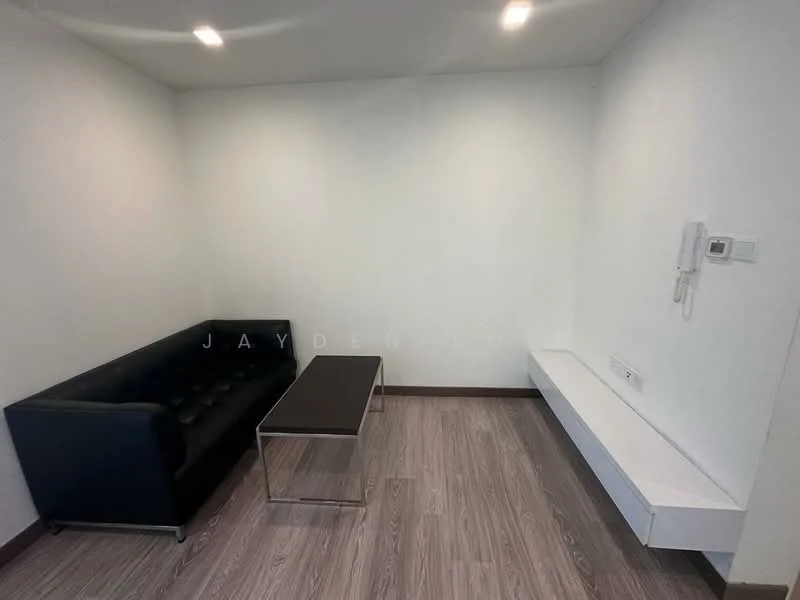 Living features: black leather sofa with tufted design, glass coffee table, white wall, wooden flooring, recessed ceiling lights, wall-mounted intercom, built-in white shelf, no visible window treatments; style: modern.
