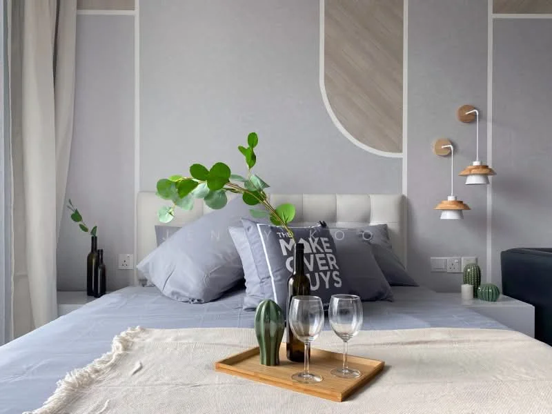Bedroom features: queen-size bed with upholstered headboard, grey bedding, decorative pillows, wooden accent wall, wall-mounted pendant lights, nightstand with green plant, decorative tray with glasses and a bottle, textured wall with geometric patterns, light-colored throw blanket, green decorative items; style: modern.