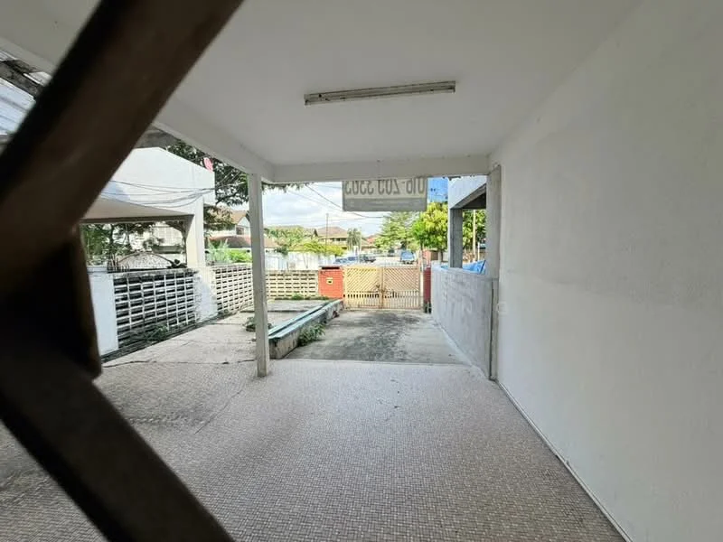 Room features: white painted walls, tile flooring, overhead fluorescent lighting, open space, view of outdoor area, access to outdoor gate, concrete flooring, windows with natural light; view: garden.