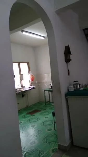 Kitchen features: green patterned vinyl flooring, white painted walls, single-bowl stainless-steel sink, window with natural light, kitchen countertop, wall-mounted light fixture, kitchen table, cabinets, appliances on countertop.