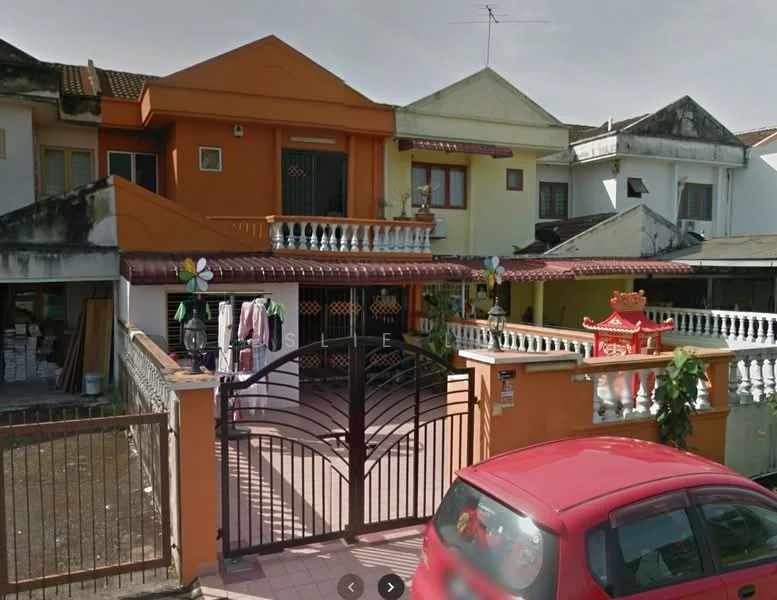 Exterior type: semi-detached house; features: orange painted facade, white railing on balcony, gated entrance with metal gate, paved driveway, decorative elements on facade, front yard with plants, clothes hanging on a line, single-storey structure, roof with tiles, visible windows with grilles; style: traditional.