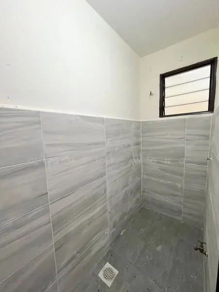 Bathroom features: grey tile cladding on walls, grey tile flooring, window with horizontal slats, drain in floor, unfinished walls, no visible fixtures.