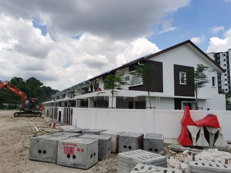 Exterior type: linked terrace house; features: two-storey building, white painted facade, brown accent panels, balconies on upper floor, manicured landscaping, construction materials visible, surrounding construction site, cloudy sky, earth-moving equipment in foreground; style: modern.