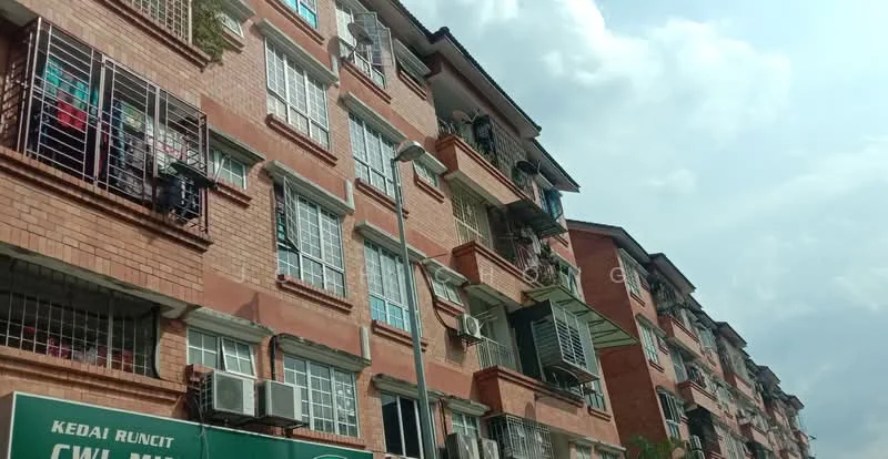 Exterior type: low-rise apartment block; features: red brick facade, multiple balconies with metal railings, window air conditioning units, visible laundry hanging on balconies, street-level signage, street lamp, partly cloudy sky; style: modern.