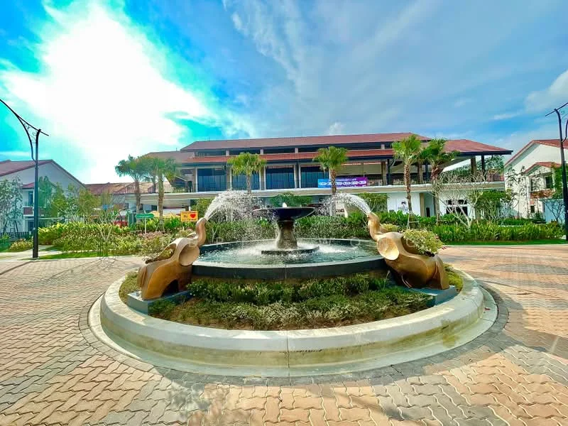 Exterior type: clubhouse; features: fountain with water jets, landscaped garden, paved walkway, surrounding palm trees, two elephant sculptures, two-storey building in background, outdoor seating area, clear blue sky; style: modern.