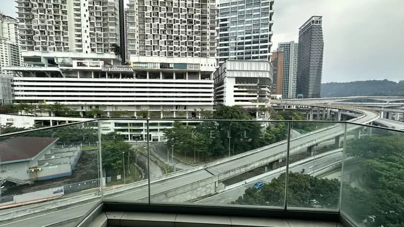 Exterior type: high-rise condominium; features: glass railing balcony, city skyline view, surrounded by urban landscape, multiple high-rise buildings, roadway visible below, greenery in foreground; style: modern.
