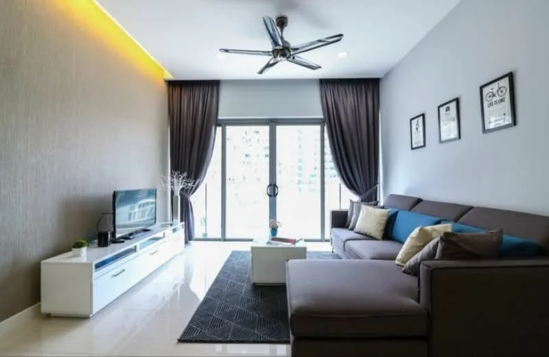 Living features: 3-seater fabric sofa in grey, 2-seater fabric sofa in brown, coffee table, TV console in white, wall-mounted TV, area rug with geometric pattern, 5-blade ceiling fan with light, floor-to-ceiling sliding glass door, blackout curtains, decorative wall art, accent pillows in blue and gold, cream painted walls, glossy tile flooring; style: modern; view: city.