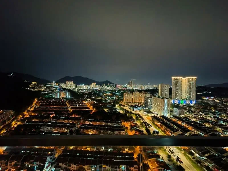 Exterior type: high-rise condominium; features: city skyline view, night lighting, surrounded by urban development, mountain backdrop, multiple high-rise buildings, street view with illuminated roads; style: modern.