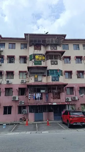 Exterior type: low-rise apartment block; features: pink painted facade, multiple levels, balconies with metal railings, window grills, air conditioning units visible, parking lot in front, red car parked, laundry hanging on balconies, signboard with contact information, satellite dish on roof; style: traditional.