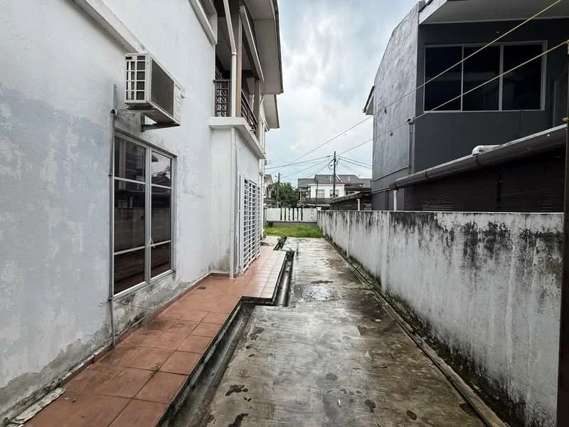 Exterior features: white painted facade, concrete wall, paved walkway, air conditioning unit on wall, fenced area, overcast sky, adjacent buildings visible; style: modern.