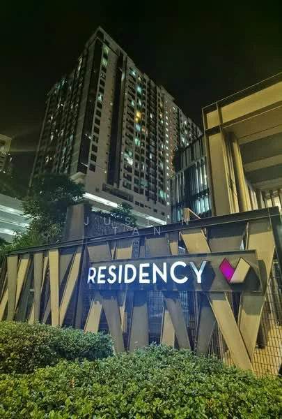 Exterior type: high-rise condominium; features: illuminated building signage, modern facade with geometric design, multiple storeys visible, surrounding greenery, night lighting, glass elements in facade; style: contemporary.