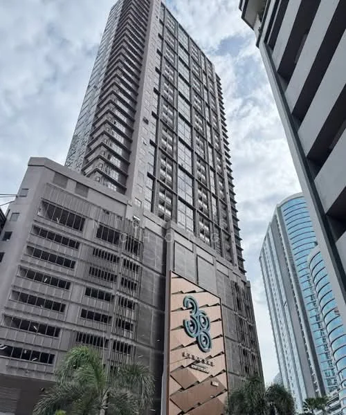 Exterior type: high-rise condominium; features: glass curtain wall, exposed concrete facade, recessed balconies, feature lighting at night, approximately 30-storey high-rise, manicured landscaping, modern architectural design, prominent building signage, surrounded by urban context; style: modern.