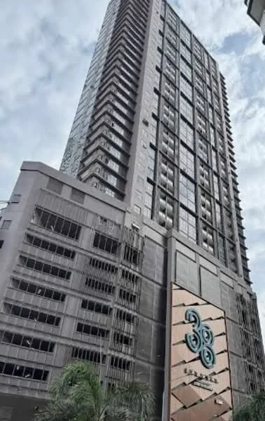 Exterior type: high-rise condominium; features: glass curtain wall, grey concrete facade, recessed balconies, feature lighting at night, approximately 30-storey high-rise, manicured landscaping, palm trees in front, main entrance with decorative feature, elevators visible, modern architectural design; style: modern.