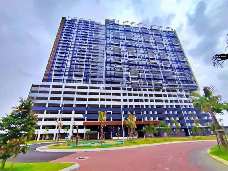 Exterior type: high-rise condominium; features: glass curtain wall, blue and white facade, multiple balconies, landscaped garden, palm trees, manicured lawn, open-air parking lot, multi-storey car park, driveway with interlocking pavers; style: modern.