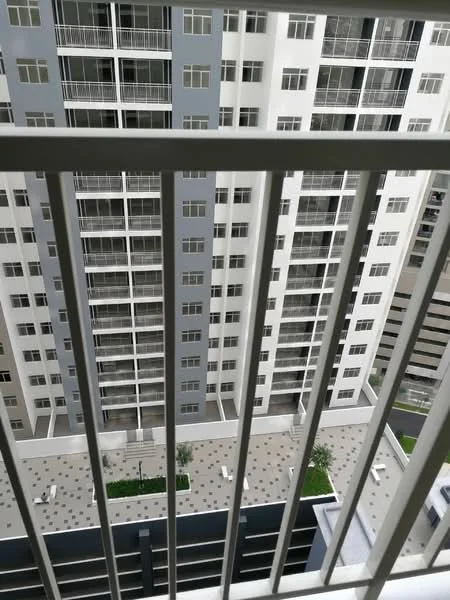 Room features: balcony with metal railing, view of adjacent building, paved outdoor area, landscaped garden, multiple windows visible in adjacent building, grey and white building facade, outdoor seating area, floor tiles in outdoor area; style: modern; view: garden.