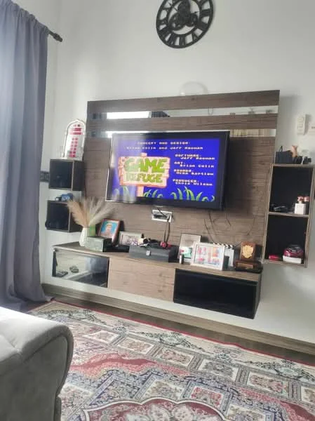 Living features: grey fabric sofa, area rug with intricate pattern, wall-mounted TV, wooden TV console, decorative wall shelves, framed artwork, wall clock, curtains, decorative plant, wooden wall paneling; style: modern.
