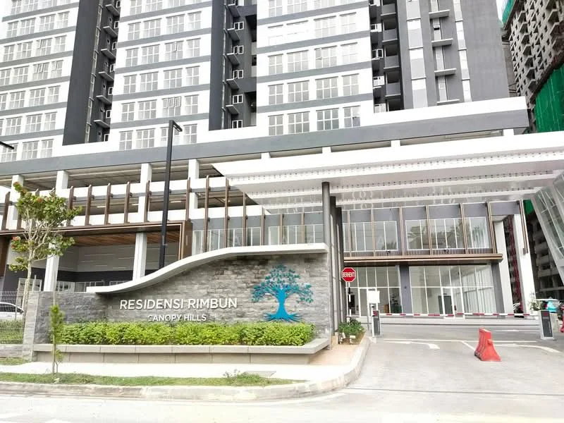 Exterior type: high-rise condominium; features: glass curtain wall, stone cladding, wooden facade elements, landscaped entrance, signage with name 'RESIDENSI RIMBUN CANDY HILLS', multiple balconies, surrounded by greenery, paved walkway, parking area, security gate, modern architectural design; style: modern.