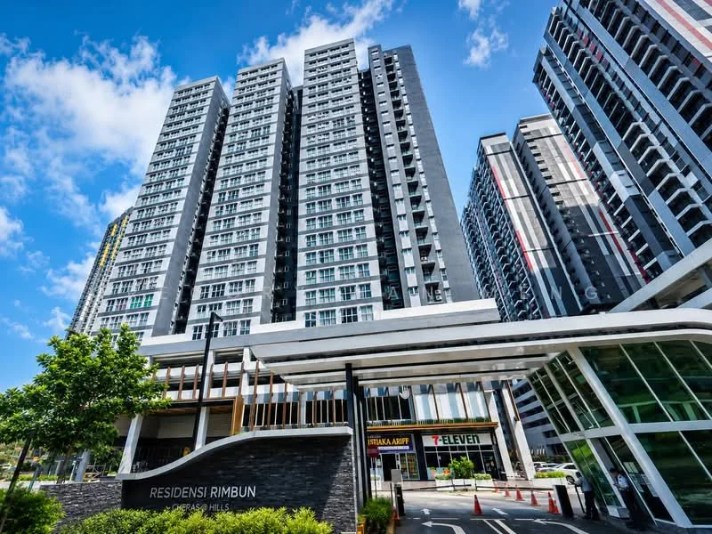 Exterior type: high-rise condominium; features: glass curtain wall, grey painted facade, recessed balconies, feature lighting at night, manicured landscaping, entrance with awning, surrounded by mature greenery, adjacent to main road; style: modern.