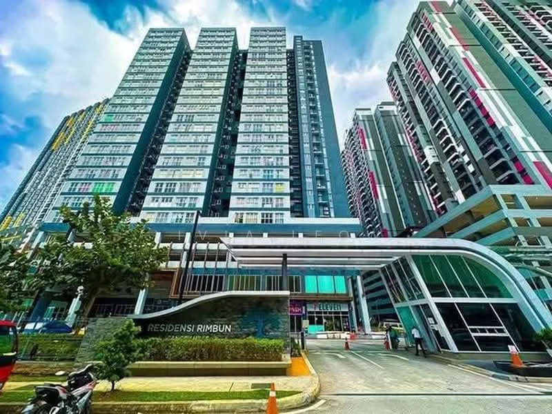 Exterior type: high-rise condominium; features: glass curtain wall, projecting balconies, manicured landscaping, modern entrance with awning, signage with 'RESIDENSI RIMBUN', multiple storeys, surrounded by greenery, driveway with interlocking pavers; style: modern.