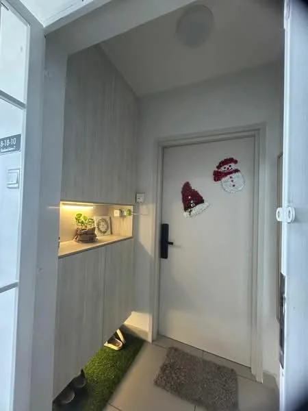 Room features: light grey wooden cabinetry, white painted walls, white door with black handle, small indoor plant on shelf, decorative wall hangings (Santa hats), grey floor tiles, recessed lighting, green carpet mat; style: modern.