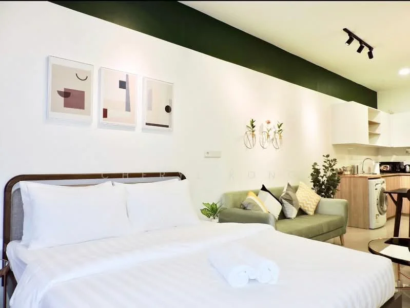 Bedroom features: queen-size bed with white bedding, upholstered headboard, 2 white towels on bed, green accent wall, white painted walls, framed abstract artwork on walls, sofa in light green fabric, decorative cushions on sofa, built-in kitchen cabinetry, washing machine, refrigerator, kitchen countertop, dining table with chairs, recessed ceiling lights; style: modern.