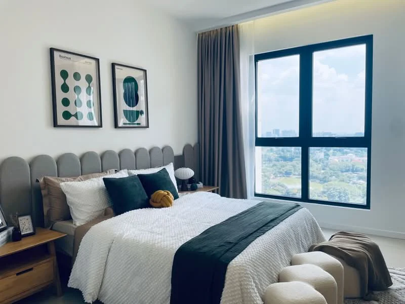 Bedroom features: king-size bed with upholstered headboard, white bedding with textured throw, green accent throw pillow, two bedside tables in wood, table lamp on bedside table, framed artwork on walls, floor-to-ceiling window, curtains in grey fabric, view of city skyline, carpeted flooring; style: modern; view: city.