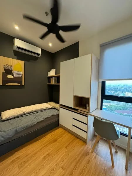Bedroom features: single bed with grey bedding, wooden flooring, dark grey accent wall, light grey wall, 5-blade ceiling fan, wall-mounted air conditioning unit, built-in wardrobe with white finish, study desk with drawers, chair, window with roller blinds, city view; style: modern; view: city.