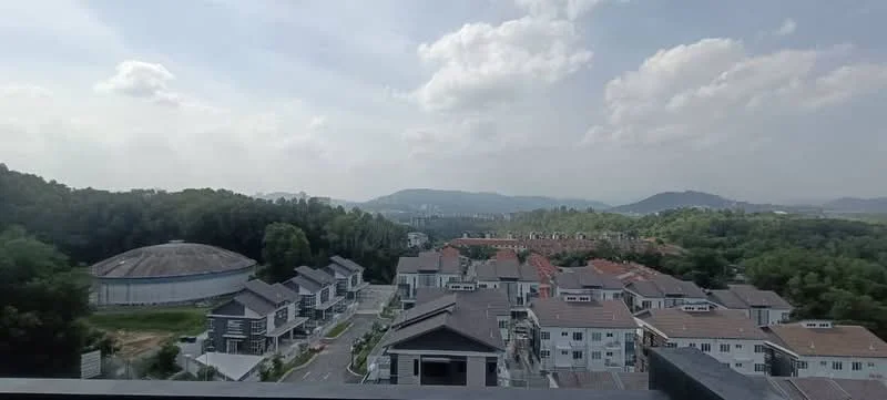 Exterior type: low-rise apartment block; features: surrounded by greenery, view of hills in background, residential area with multiple buildings, road access visible, open space in foreground, cloudy sky; style: modern.