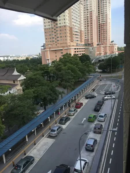 Exterior type: high-rise condominium; features: glass curtain wall, cream painted facade, surrounded by mature greenery, open-air parking lot, covered walkway, adjacent to highway; style: modern.