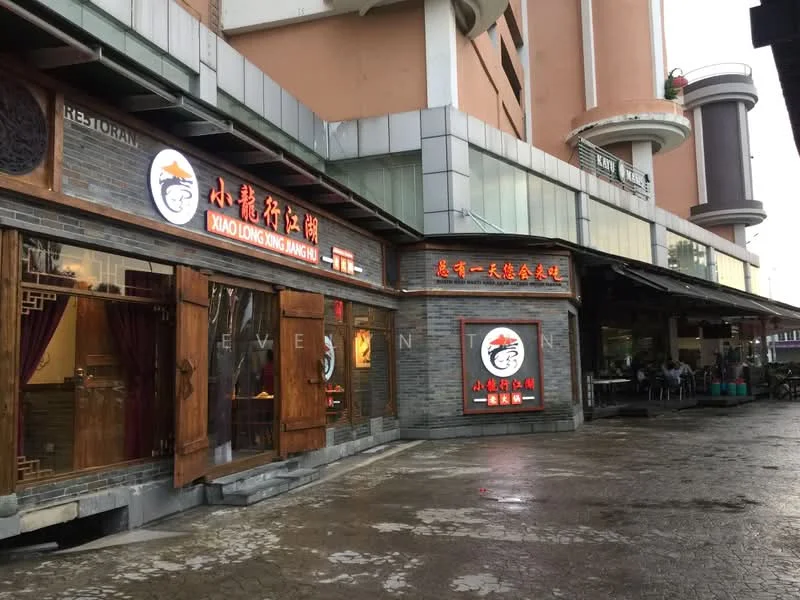 Exterior features: brick facade, wooden doors, illuminated signage, outdoor seating area, paved walkway, multi-storey building in background; style: traditional.