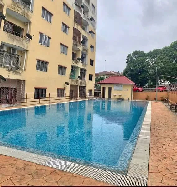 Exterior type: low-rise apartment block; features: swimming pool, pool deck, yellow painted facade, multiple air conditioning units visible, surrounding greenery, outdoor seating area, paved walkway, single-storey clubhouse, parking area visible in background; style: modern.