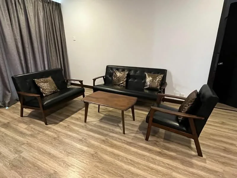 Living features: 2-seater black leather sofa, 3-seater black leather sofa, wooden coffee table, decorative cushions with metallic sheen, laminate flooring, grey curtains, neutral wall color, wooden armrests on sofas; style: modern.
