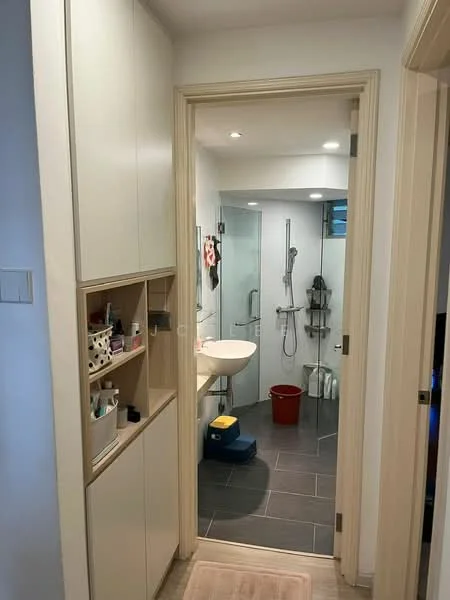 Room features: light grey tiled flooring, white painted walls, recessed downlights, built-in cabinetry with open shelving, sink with wall-mounted faucet, shower area with glass enclosure, handheld shower, shower rail, toilet, red bucket, blue storage container; style: modern.