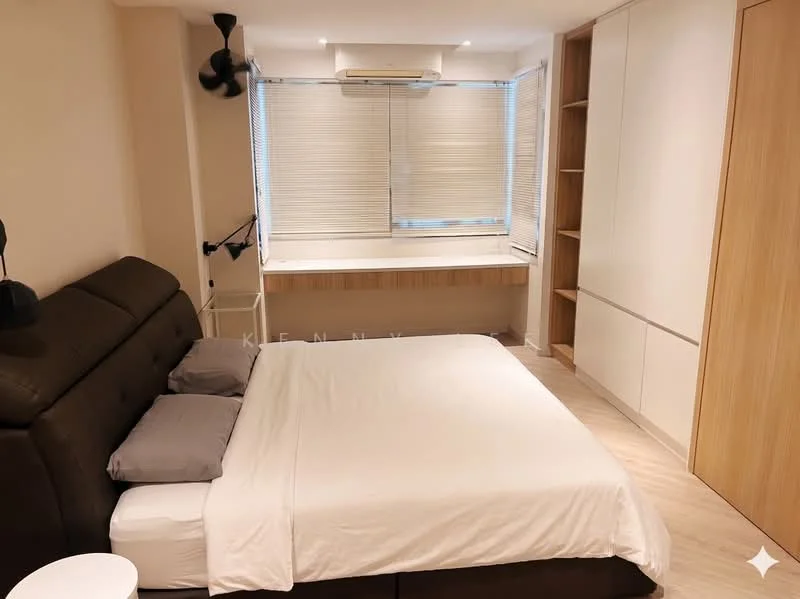 Bedroom features: king-size bed with upholstered headboard, 2 grey pillows, wooden bedside table, wall-mounted reading light, built-in wardrobe with sliding doors, window with blinds, desk area with wooden surface, light-colored laminate flooring, ceiling-mounted fan, air conditioning unit; style: modern.
