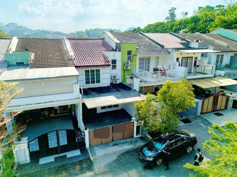 Exterior type: linked terrace house; features: two-storey linked terrace, brown painted facade, red tile roof, balconies on upper floors, manicured front garden, driveway with interlocking pavers, visible air conditioning units, surrounded by greenery, car parked in front, street view, gated entrance; style: modern.