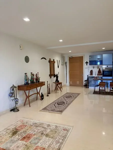 Room features: cream painted walls, polished marble flooring, recessed downlights, decorative wall art, wooden console table, decorative sculptures, area rug with geometric pattern, wooden door, open kitchen area visible in background; style: modern.