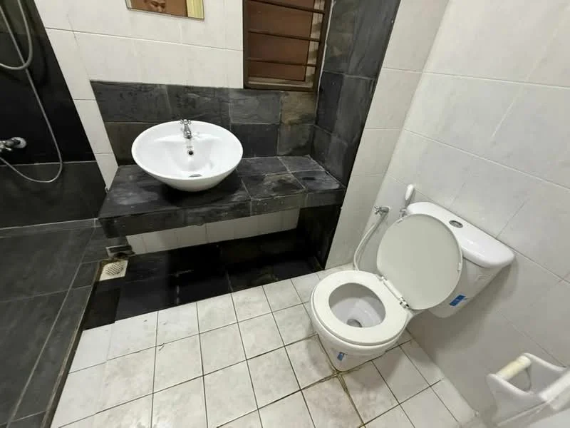 Bathroom features: white ceramic toilet, single-sink vanity with wall-mounted basin, black stone countertop, grey tiled walls, white tiled flooring, shower with glass partition, chrome showerhead, window for natural light, wall-mounted mirror; style: modern.