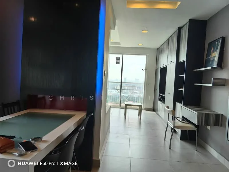 Living features: floor-to-ceiling windows, city view, light grey tiled flooring, black accent wall, built-in shelving unit, wall-mounted TV, recessed lighting, dining table with green tabletop, black dining chairs, open layout, neutral wall color, sliding glass door to balcony; style: modern; view: city.