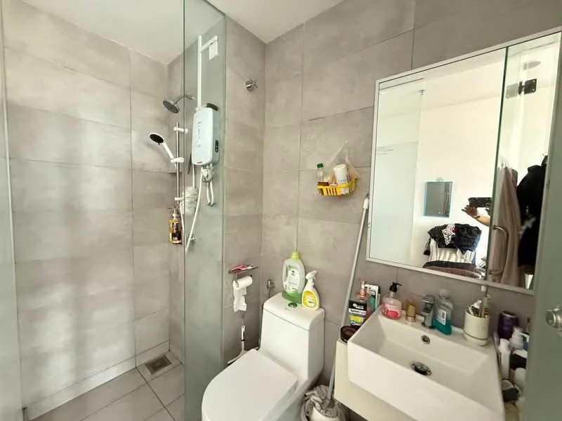 Bathroom features: walk-in shower with glass enclosure, rain shower head, handheld shower, chrome basin mixer, one-piece toilet, single-sink vanity with white cabinet, mirror above sink, grey tiled walls, grey tiled flooring, wall-mounted shower caddy, various toiletries on vanity; style: modern.