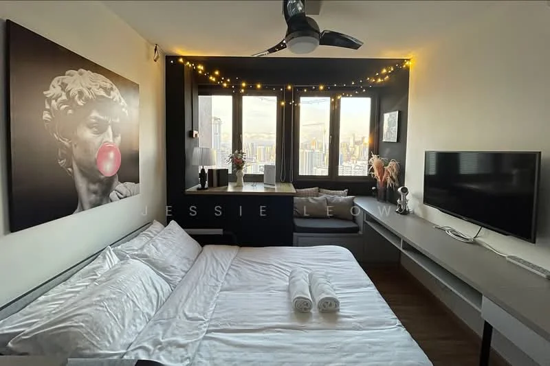 Bedroom features: queen-size bed with white bedding, upholstered headboard, 2 white towels on bed, large artwork of a statue with bubble gum, floor-to-ceiling windows with city view, window seat with cushions, LED fairy lights along the wall, wooden flooring, ceiling fan, wall-mounted TV, built-in shelving unit; style: modern; view: city.