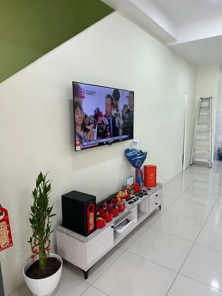 Living features: white painted walls, green accent wall, glossy ceramic tile flooring, wall-mounted TV, TV console in light wood, decorative plant in pot, decorative items on console, step ladder in background; style: modern.