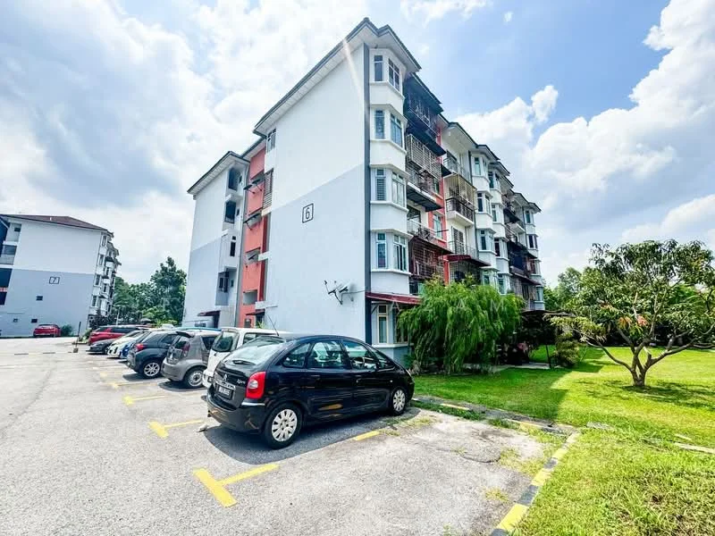 Exterior type: low-rise apartment block; features: white painted facade, red accent panels, multiple balconies, landscaped green area, manicured lawn, parking spaces, surrounding trees, cloudy sky, asphalt parking lot; style: modern.