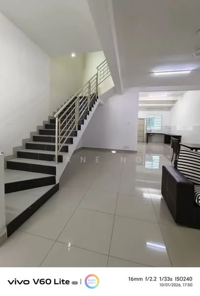 Room features: white painted walls, grey tiled flooring, staircase with metal railing, large windows for natural light, open layout, ceiling lights, corner sofa in dark color, neutral color palette; style: modern.